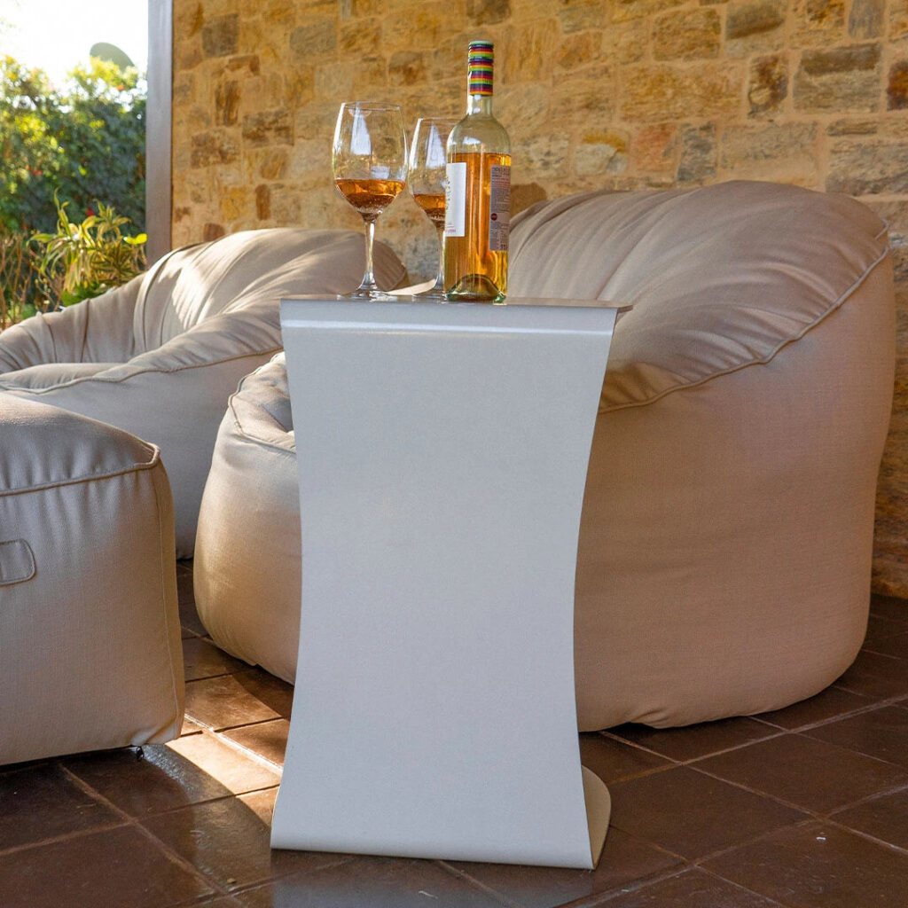 Mesa lateral elegante com taças de vinho em uma área aberta da casa, decorada com móveis aconchegantes e detalhes rústicos