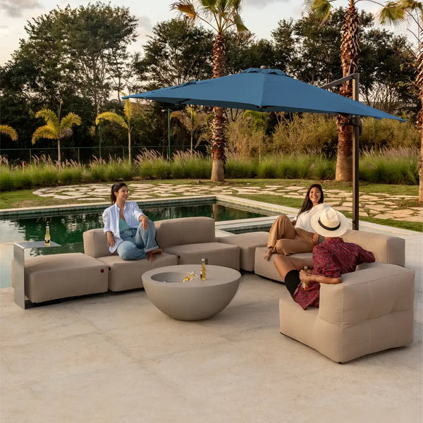 Espaço ao ar livre com sofá modular e ombrelone azul, ideal para festas à beira da piscina e momentos de descontração.  A imagem ilustra uma decoração de réveillon na piscina.
