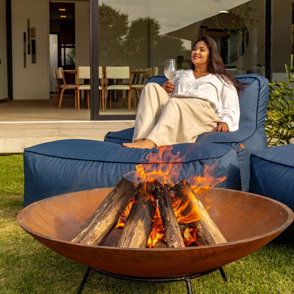 Poltrona azul com lareira de tacho ao centro, perfeita para decorar jardim e criar um ambiente acolhedor ao ar livre.