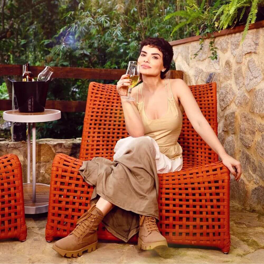 Poltrona tramada laranja com champanheira ao lado, combinando estilo rústico e moderno para decorar jardim.