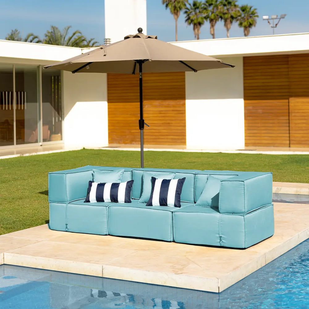 Sofá modular azul com almofadas listradas e um ombrelone ao lado da piscina, ideal para decoração para jardim externo sofisticado.