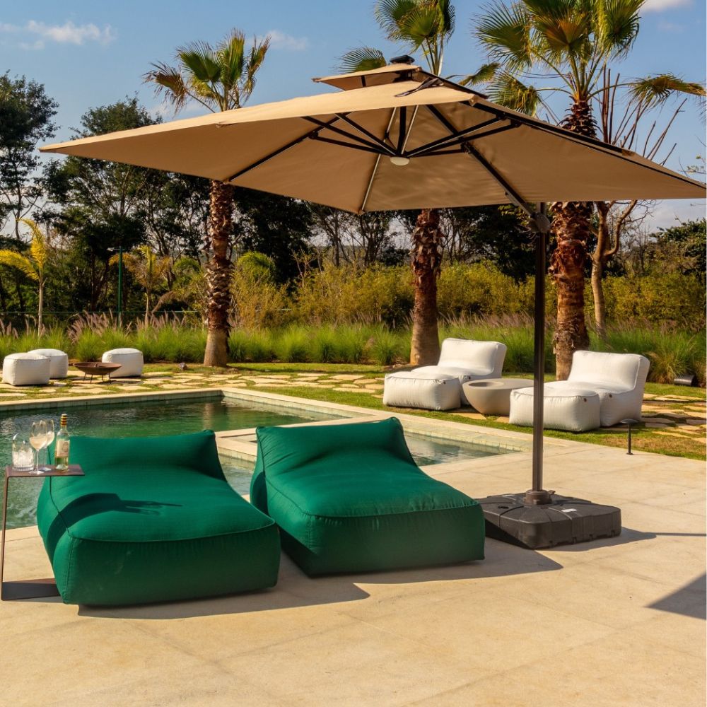 Espreguiçadeiras verdes com ombrelone ao lado da piscina, trazendo ideias para área externa funcional e elegante.